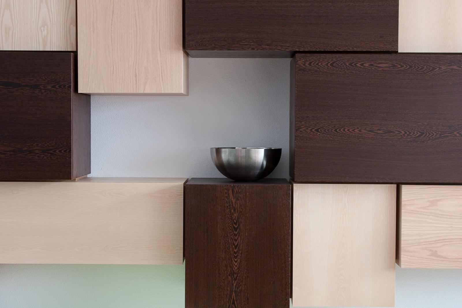 Wandkast met blokvormige volumes in wengé, essen en berken multiplex.