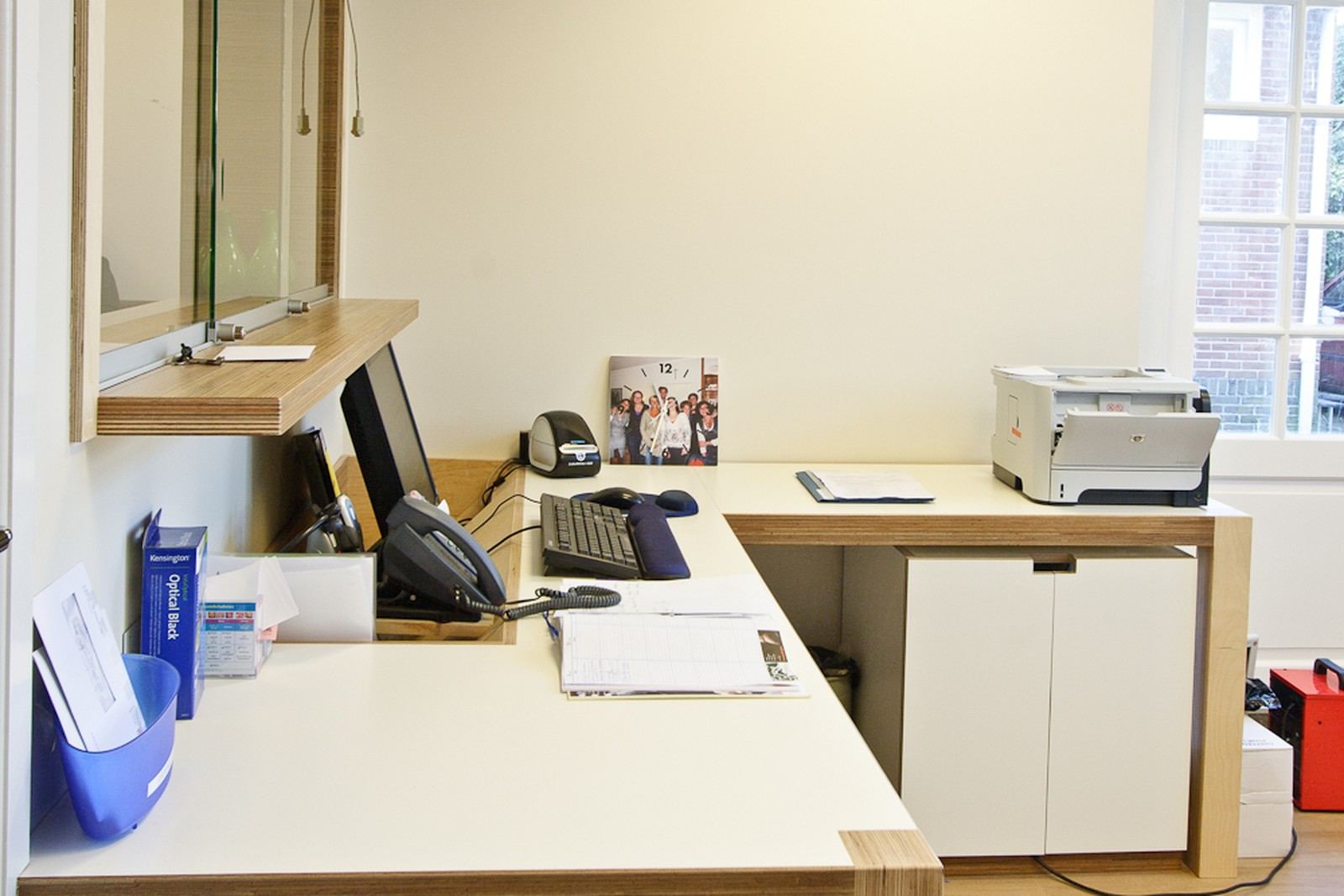 Balie met wit werkblad en wengé rand, onder een schuifraam.
