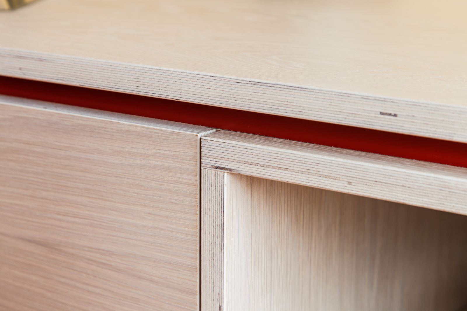 Detail van de rode binnenzijde van een open vak in het dressoir.