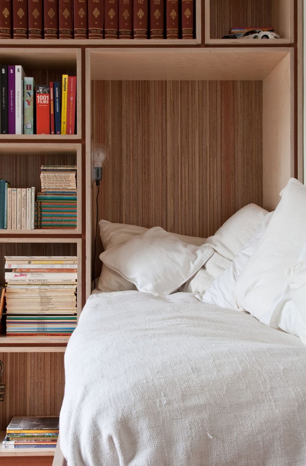 Bedniche in gestreept plexwood met kussens en een leeslampje.