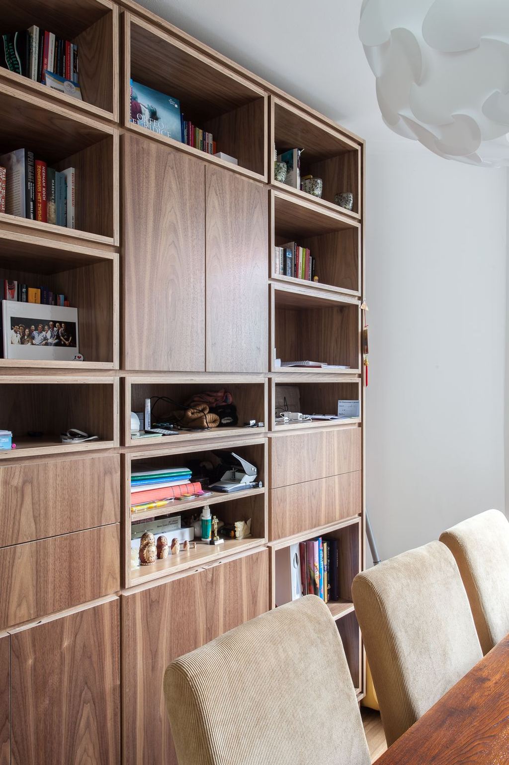 Notenhouten kastenwand met boeken, foto's en een rij poppetjes.