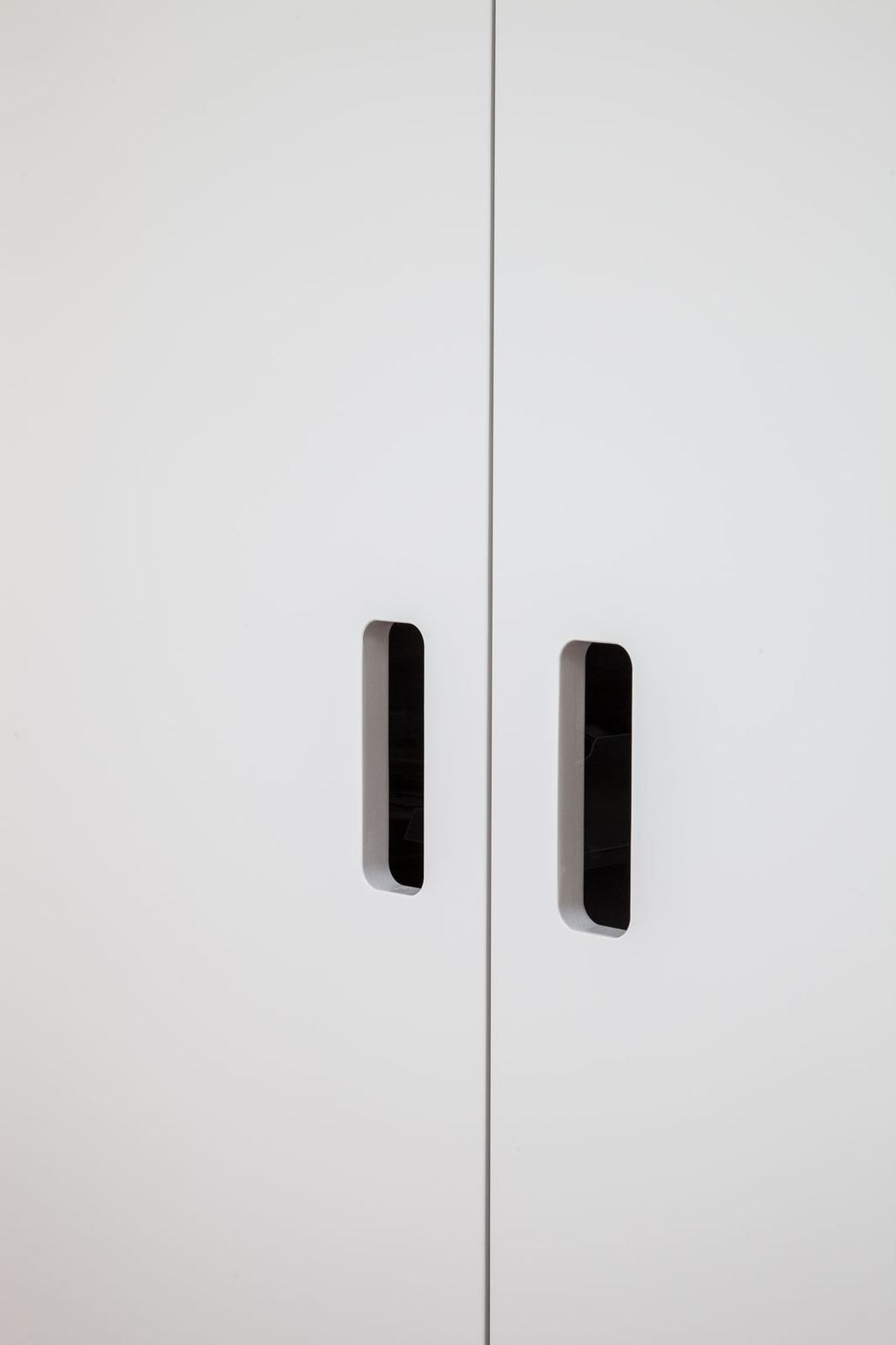 Detail van twee smalle greepjes in de kastdeuren.