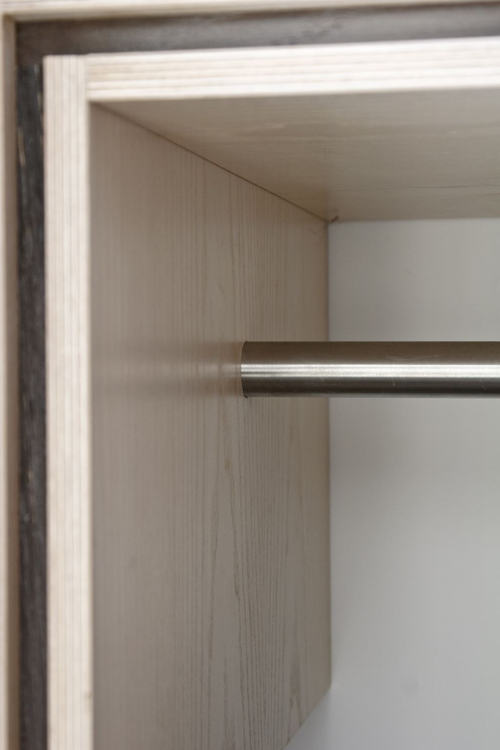 Detail van de bevestiging van de kledingstang in de kast.