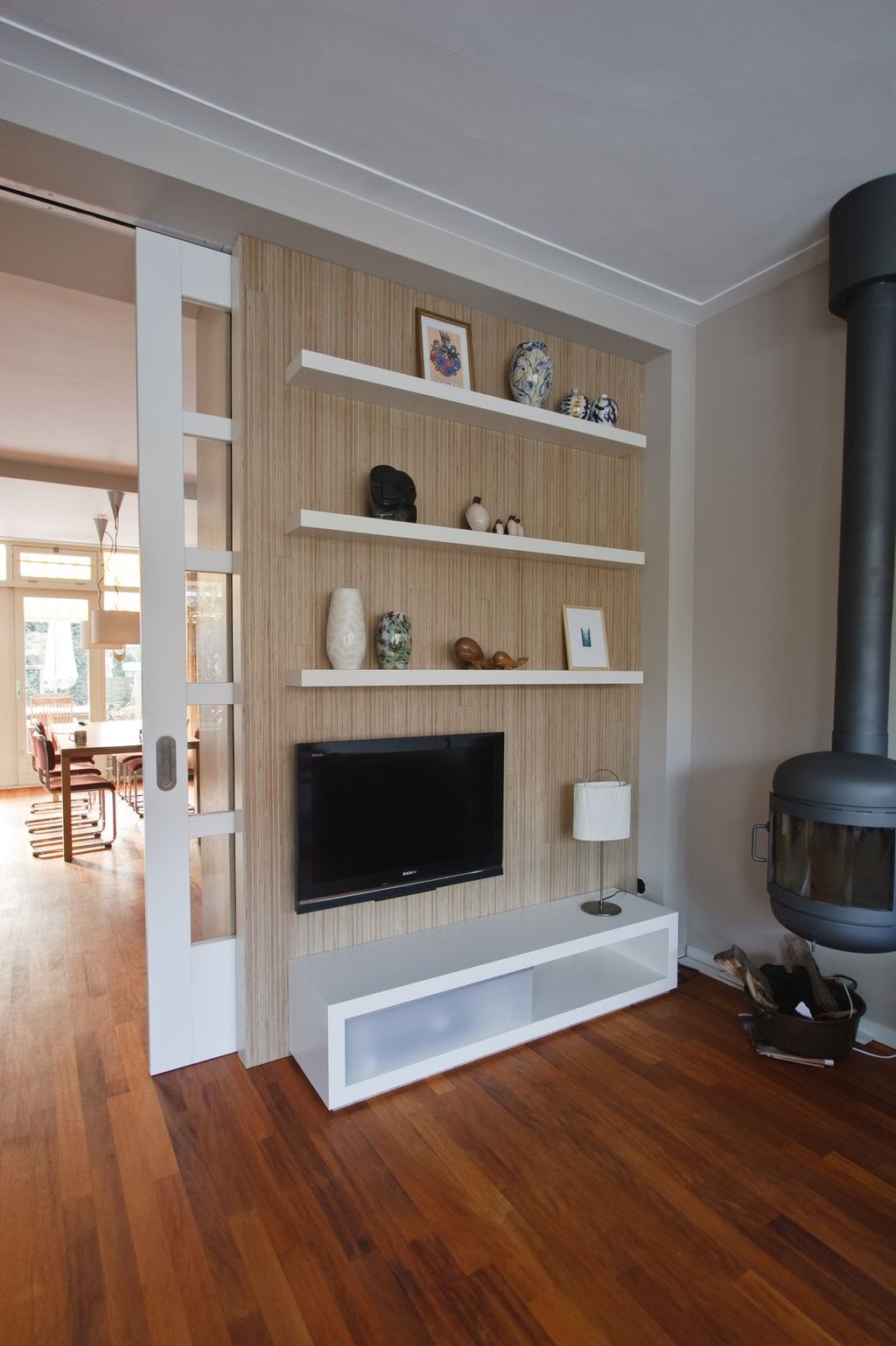 Televisiekast met houten wandpaneel, zwevende planken en een tv.