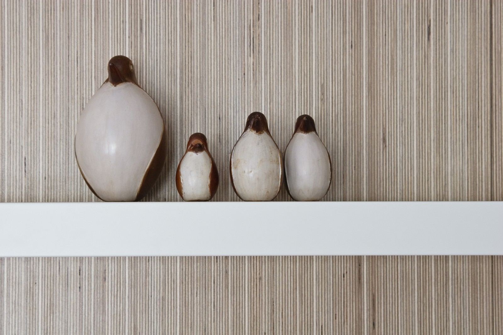 Close-up van vier kleine vogelbeeldjes op een plank.