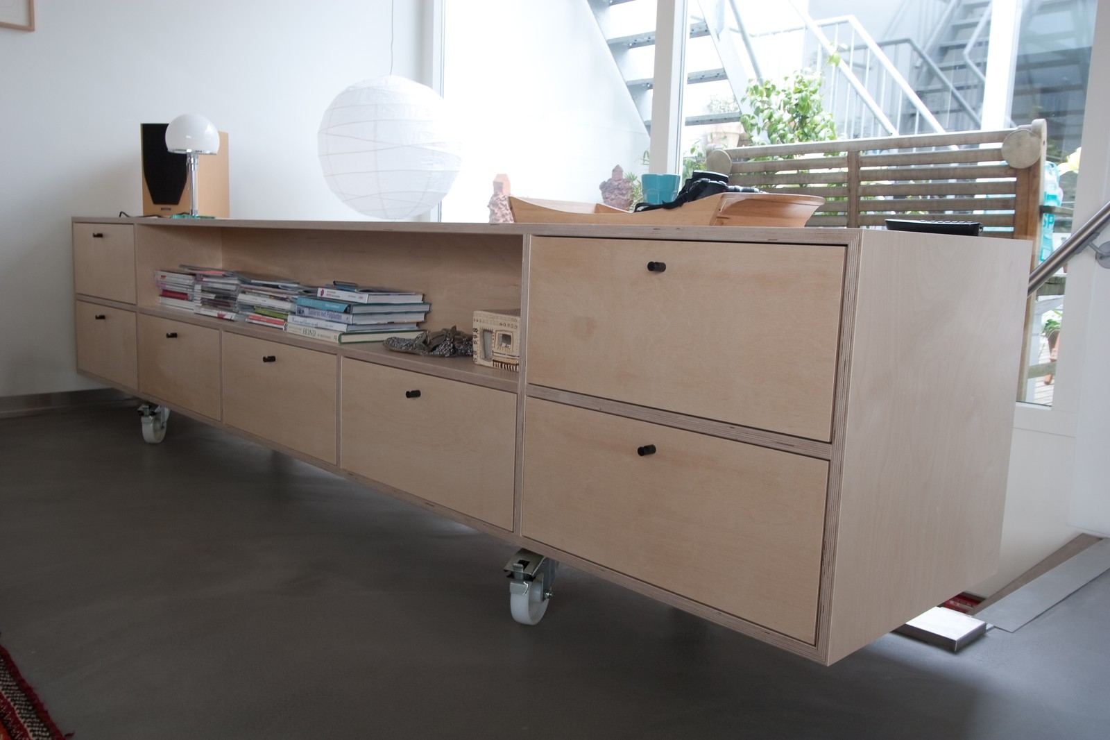 Lang zwevend dressoir met een open vak vol boeken en een rij brede laden.