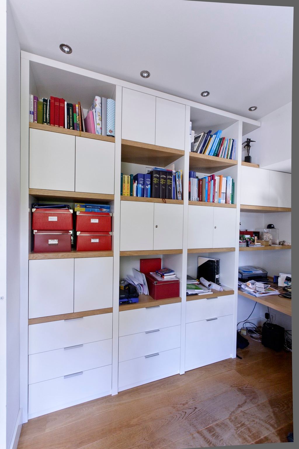 Boekenkast met witte kastdeuren en open eiken planken vol boeken.
