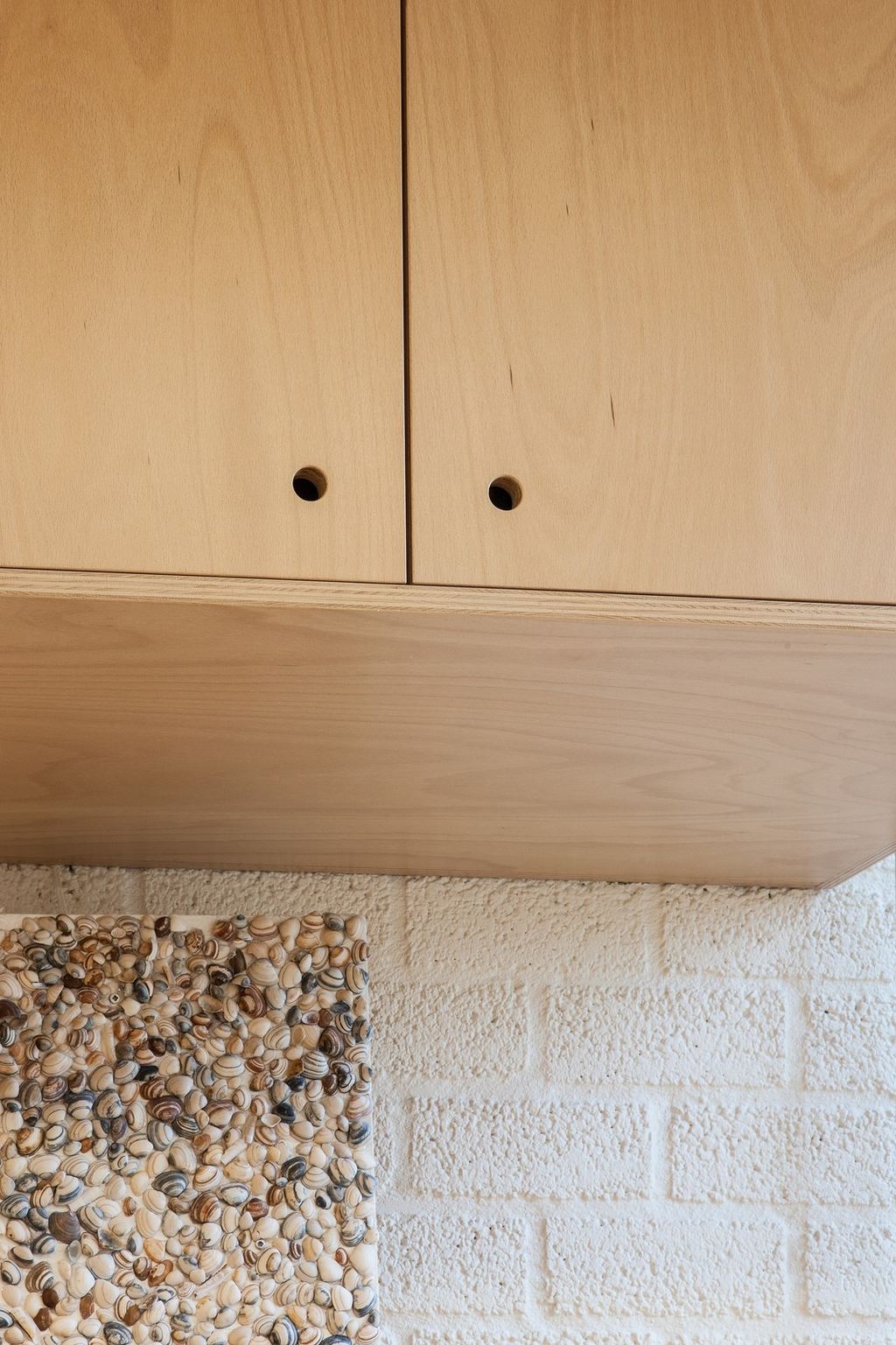 Detail van de onderzijde van een wandkast in berken multiplex.
