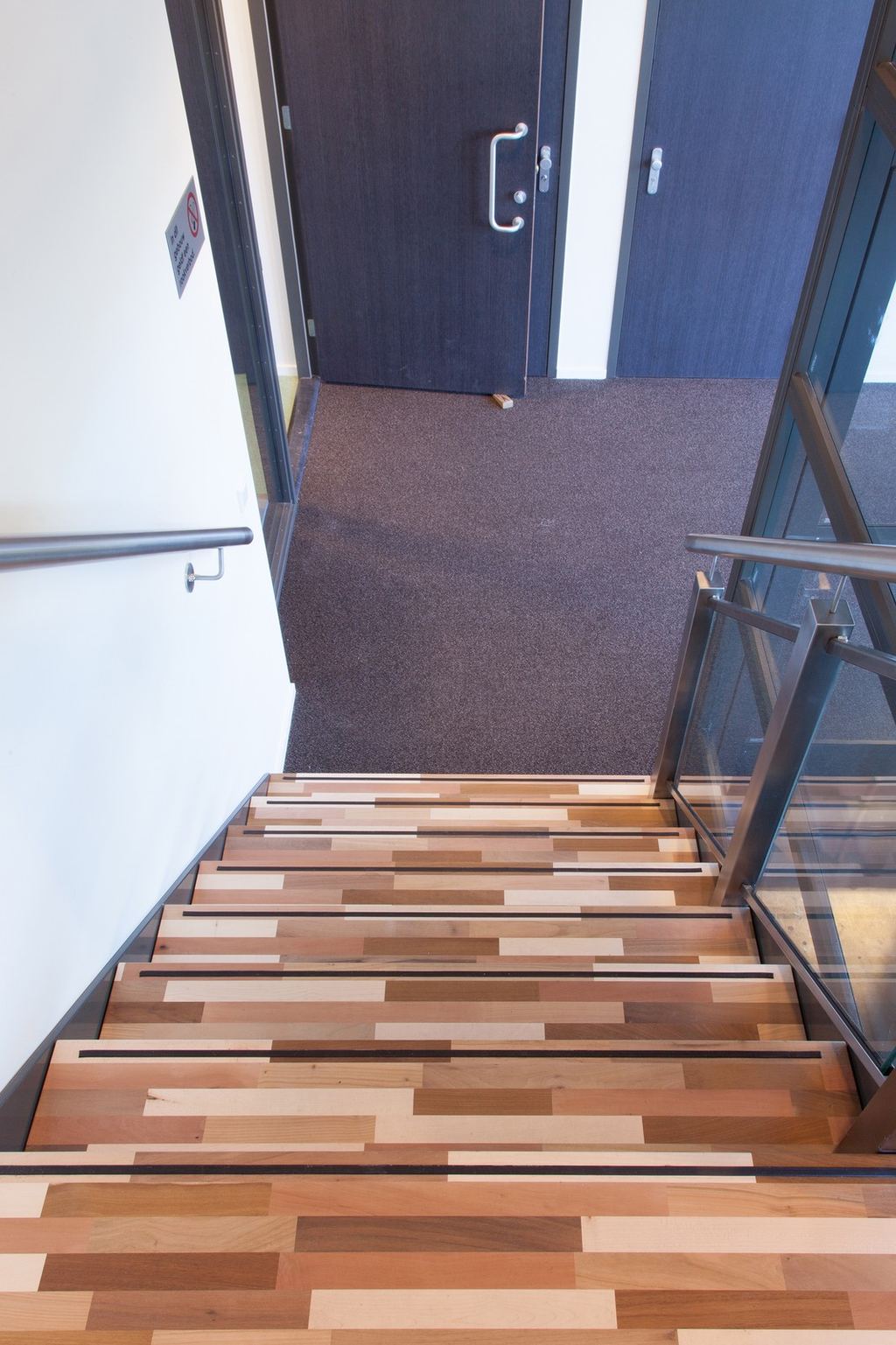 Trap geflankeerd door een glazen balustrade en stalen leuning.