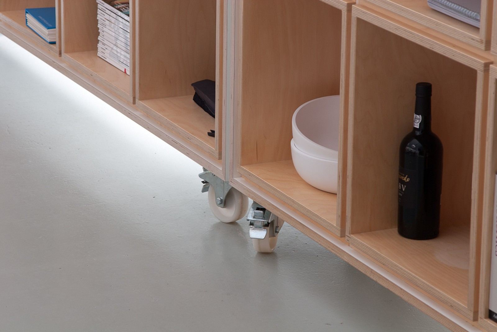 Detail van een wiel onder de kast, met vakken vol serviesgoed.