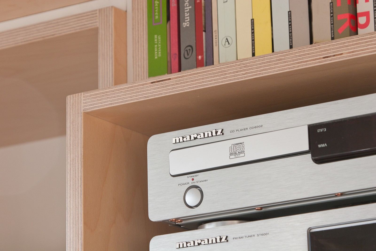 Detail van een vak met boeken boven de stereo-apparatuur in de kast.