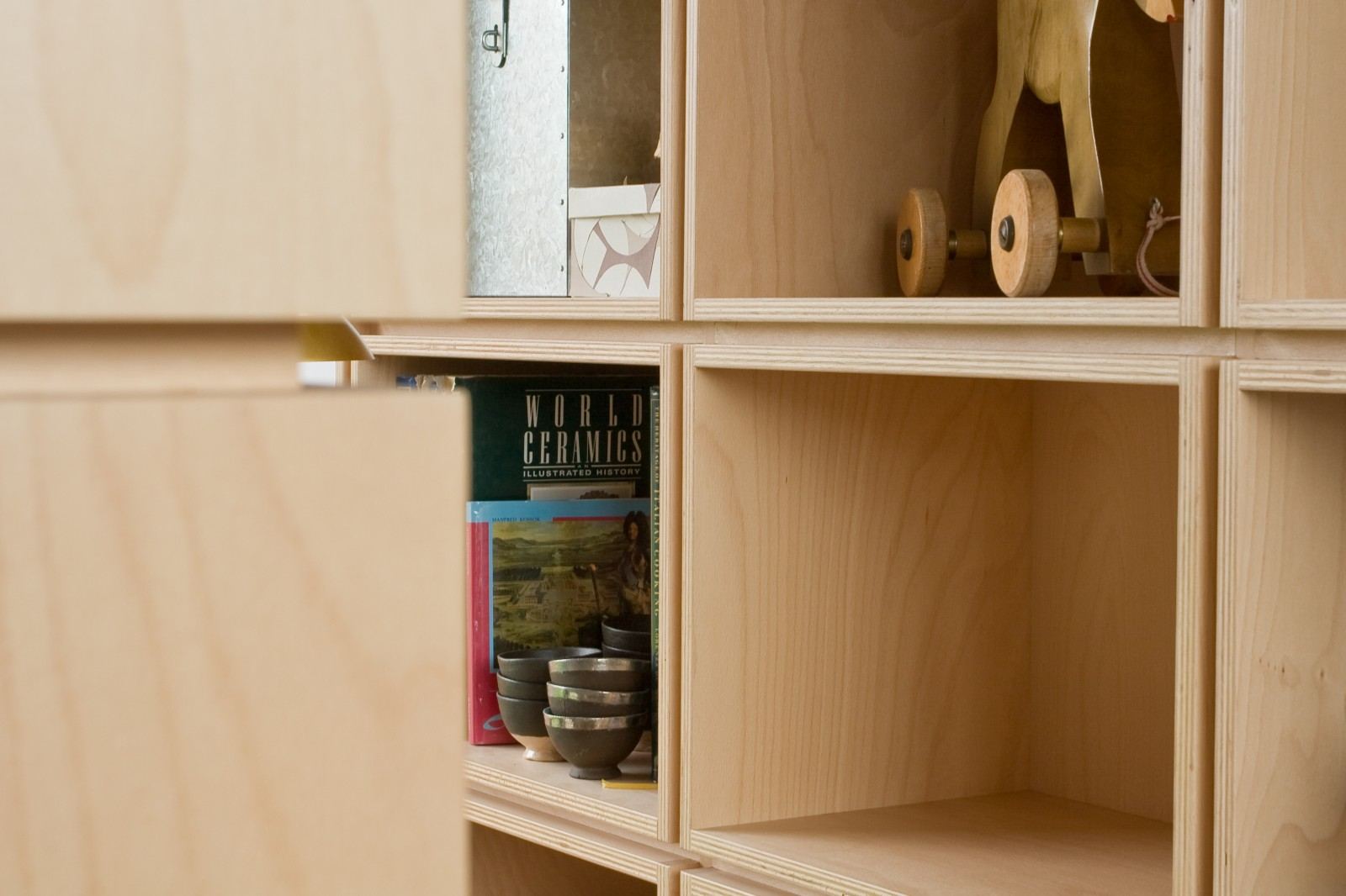 Vakken met een houten speelgoedpaard, kommen en een boek.