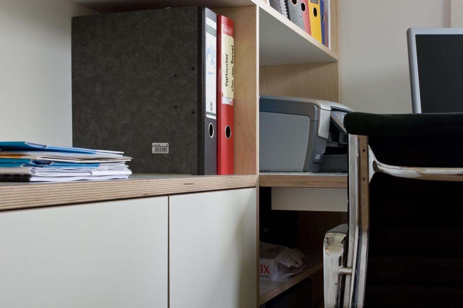 Boekenkast met open vakken en witte kastdeuren naast een printerplank.