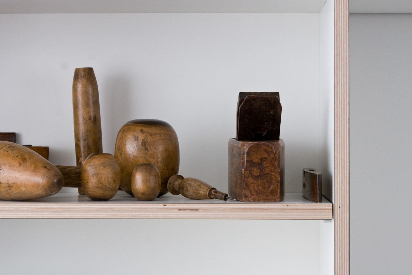 Houten voorwerpen en gereedschap uitgestald op een open plank.