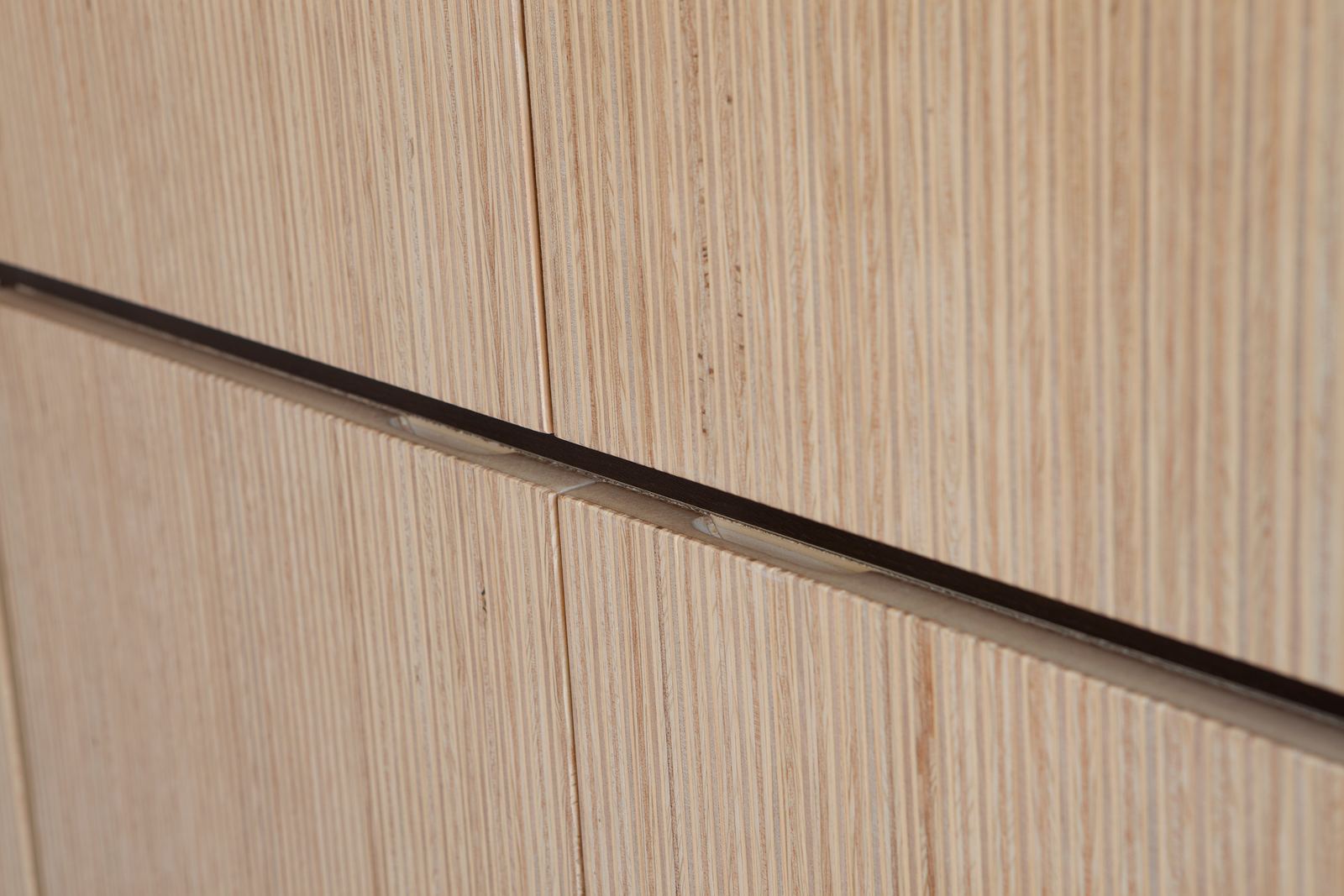 Detail van de ingefreesde greeplijst tussen twee kastdeuren.